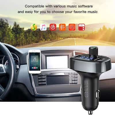 A car interior featuring a mounted smartphone displaying a music app, the BASEUS Wireless Bluetooth FM Transmitter & MP3 Music Player with Dual USB Car Charger plugged into the console. There's also a dual USB car charger included, ensuring you're always powered up. Text above states compatibility with various music software.