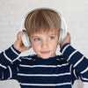Young child in striped shirt wearing BELKIN SoundForm Mini Wireless - On-Ear Headphones for Kids - White.