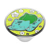 Colorful illustration of a cartoon cat lounging on a field of flowers, encapsulated within a circular frame atop a PopSockets PopGrip Licensed - Bulbasaur Nap stand designed for wireless charging.
